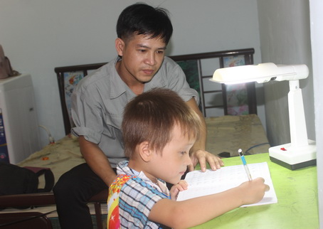 Anh Phạm Văn Bình, công nhân Công ty cổ phần công nghiệp chính xác Việt Nam (VPIC) kèm con tập viết chữ trong căn phòng do công ty đầu tư xây dựng.