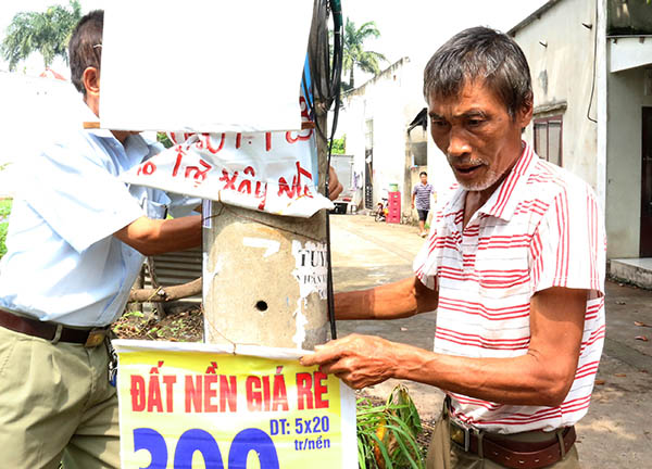 Ông Nguyễn Văn Luật (58 tuổi) ngụ KP.5, phường Hố Nai (TP.Biên Hòa) cùng bà con trong khu phố gỡ những quảng cáo mua bán đất được treo, dán trên cột điện làm mất mỹ quan đường phố. Ảnh: V.TUYÊN