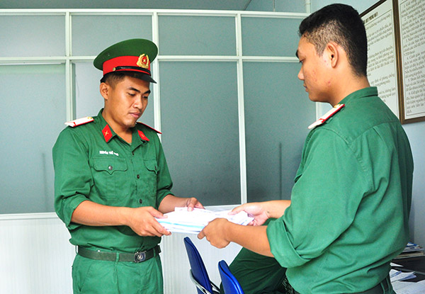 Binh nhì Nguyễn Thế Hùng (trái) nhận công văn tại Trạm quân bưu đơn vị trước khi đi giao.