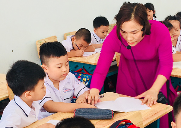 Một giáo viên của trường tiểu học Nguyễn Thái Học(phường Trảng Dài,TP.Biên Hòa) phải dùng thiết bị âm thanh di động hỗ trợ dạy học sinh lớp 1
