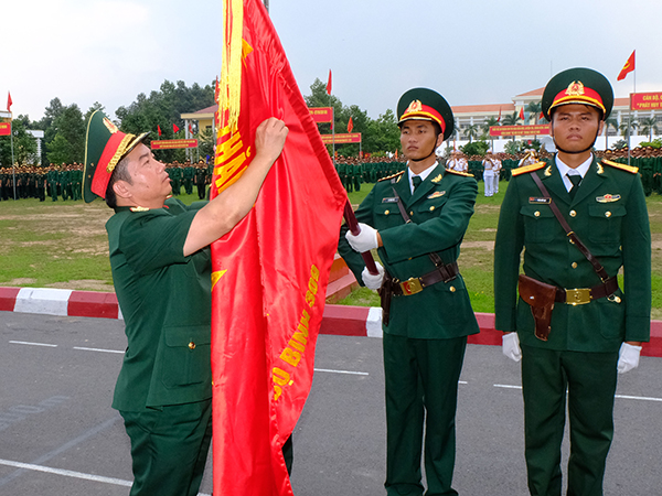 Thiếu tướng Nguyễn Xuân Sơn, Chính ủy Quân đoàn 4 gắn huân chương Bảo vệ Tổ quốc hạng Ba lên quân kỳ quyết thắng của Sư đoàn 309. (Ảnh: Đăng Tùng)