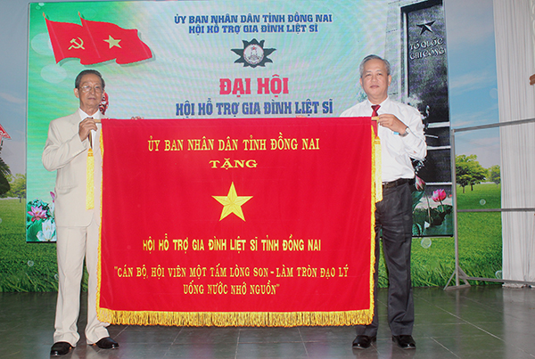 Ông Huỳnh Văn Tịnh, Giám đốc Sở Lao động – thương binh và xã hội trao bức trướng của UBND tỉnh cho đại diện Ban chấp hành Hội hỗ trợ gia đình liệt sĩ tỉnh khóa II