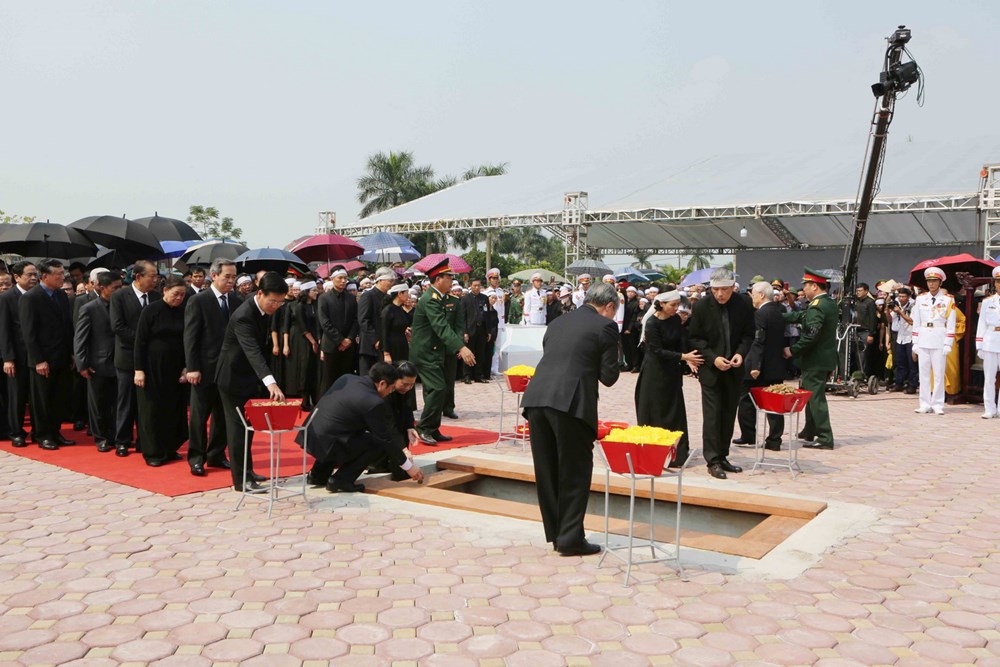 Các đồng chí lãnh đạo, nguyên lãnh đạo Đảng, Nhà nước, Mặt trận Tổ quốc Việt Nam thả những nắm đất đầu tiên xuống huyệt mộ nguyên Tổng Bí thư Đỗ Mười. (Ảnh: Dương Giang/TTXVN)