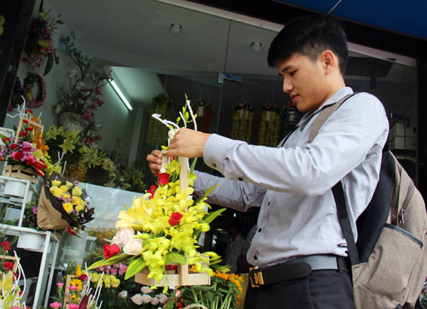 Khách hàng đang chọn mua hoa tại một cửa hàng hoa tươi ở gần khu vực chợ Tân Hiệp (TP.Biên Hòa) vào sáng 19-10. 