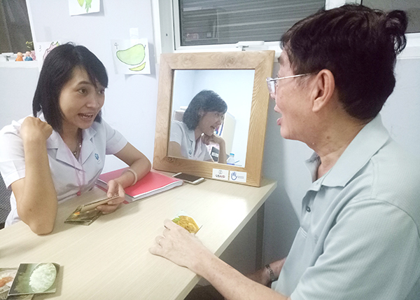 Kỹ thuật viên Lê Ngọc Phượng đang luyện tập phát âm cho ông Ngô Văn Thanh