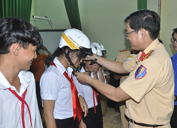 Cán bộ Phòng Cảnh sát giao thông Công an tỉnh tặng mũ bảo hiểm cho học sinh Trường THCS-THPT Huỳnh Văn Nghệ (xã Phú Lý, huyện Vĩnh Cửu).