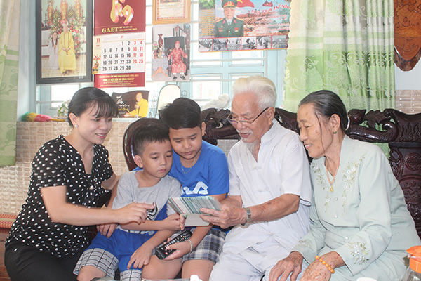 Ông Trần Kim Tuyến và bà Tống Thị Hương Tiêu cùng con dâu và các cháu đang xem lại những hình ảnh của gia đình.