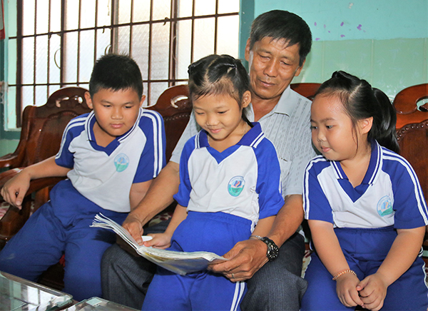 Ông Ân Đức Tiến (dân tộc Hoa, ngụ thị trấn Tân Phú, huyện Tân Phú) đọc truyện cho các cháu nghe.