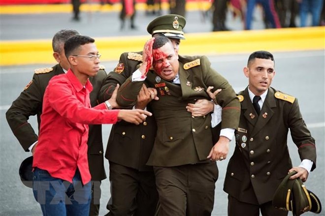 Lực lượng an ninh Venezuela hỗ trợ một đồng đội bị thương rời khỏi hiện trường vụ tấn công tại lễ kỷ niệm Ngày Quốc phòng ở thủ đô Caracas ngày 4/8. (Nguồn: THX/TTXVN)