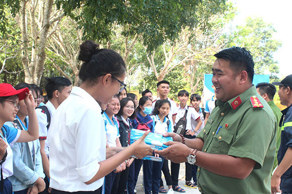 Anh Huỳnh Minh Đức, Phó bí thư Đoàn Thanh niên Công an tỉnh trao quà cho các em học sinh ở huyện Xuân Lộc khi tham gia trả lời các câu hỏi về phòng cháy, chữa cháy Ảnh: N.Sơn