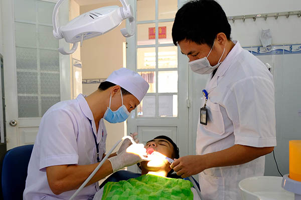 Bác sĩ Nguyễn Viết Tuấn (bìa trái) Bệnh xá trưởng Bệnh xá Trường đại học Nguyễn Huệ chữa răng cho bệnh nhân