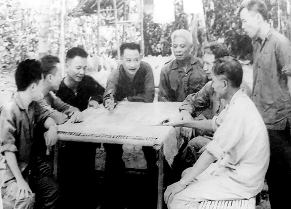 Trung tướng Trần Văn Trà - Tư lệnh Bộ Chỉ huy miền Nam (người đang chỉ tay trên bản đồ) và Tham mưu trưởng Lê Đức Anh (người ngồi bên phải Trung tướng Trần Văn Trà) trong cuộc họp Bộ Chỉ huy miền Nam tại Căn cứ Lộc Ninh (Bình Phước) năm 1972