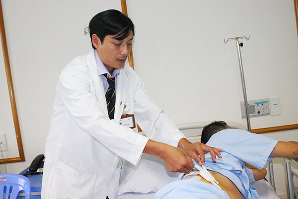  Bác sĩ Bùi Khắc Thái kiểm tra vết mổ cho bệnh nhân G. trước khi bệnh nhân được xuất viện.