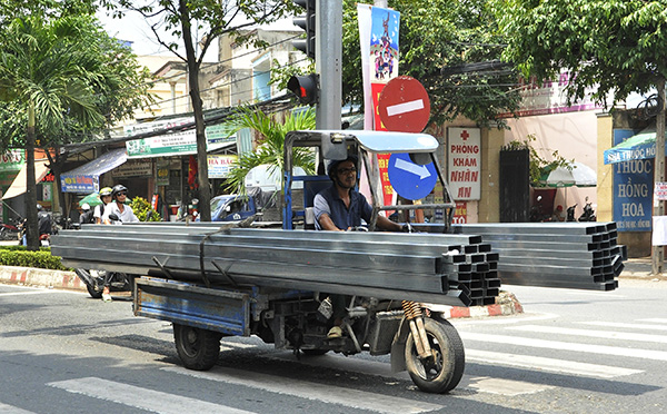Một xe ba gác chở thép ống không được che đậy cẩn thận khi lưu thông qua khu vực phường Trảng Dài (TP.Biên Hòa). Ảnh: T.HẢI