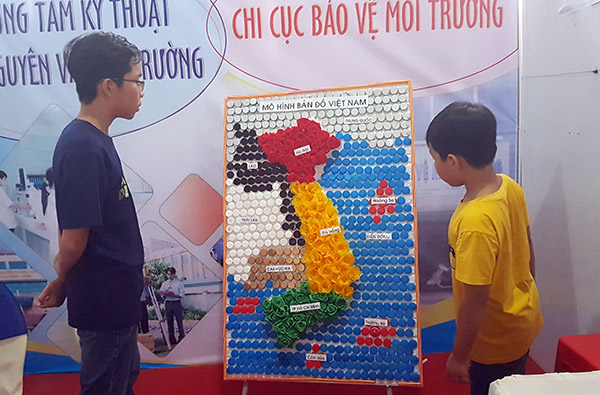 Các em nhỏ xem mô hình bản đồ Việt Nam được láp ghép từ nút chai.