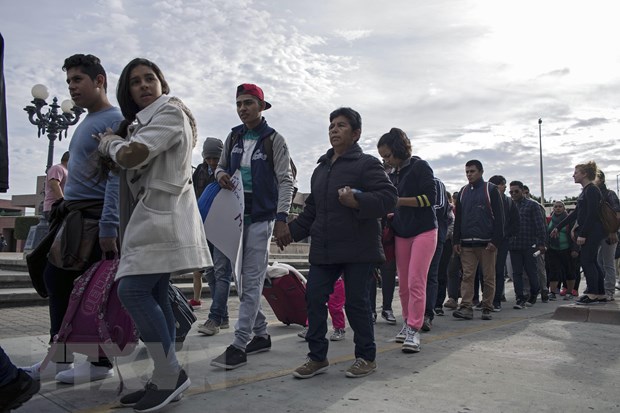Người di cư Trung Mỹ vượt qua hàng rào biên giới khi di chuyển từ Tijuana, bang Baja California (Mexico) tới San Diego, Mỹ, ngày 21-3-2019. (Nguồn: AFP/TTXVN)