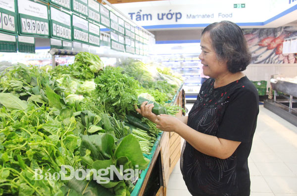 Khách hàng chọn mua rau được gói bằng lá chuối tại Co.opmart Biên Hòa. Ảnh: Hải Quân