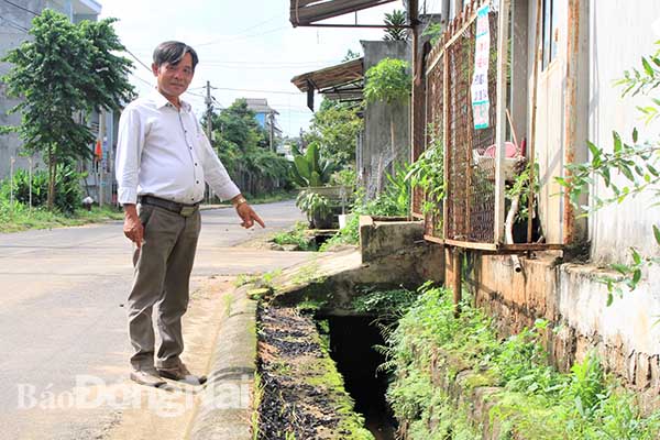 Ông Phạm Văn Thuận bên đoạn cống thoát nước được ông giám sát quá trình xây dựng và tiếp thu ý kiến người dân để kiến nghị với huyện điều chỉnh thiết kế