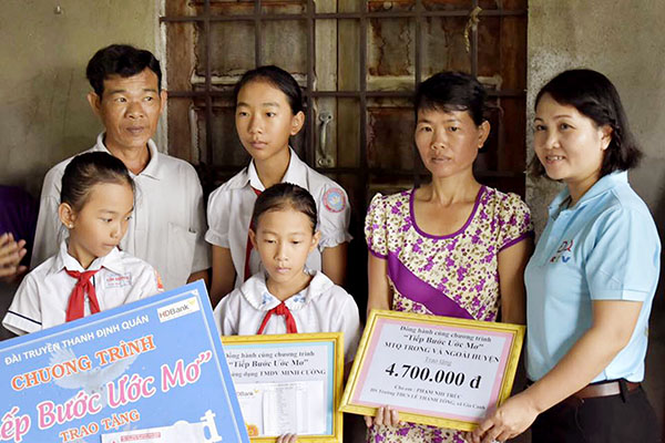 Đại diện nhóm thực hiện chương trình Tiếp bước ước mơ (bìa phải) Đài Truyền thanh huyện Định Quán trao quà cho gia đình một học sinh nghèo ở xã Gia Canh