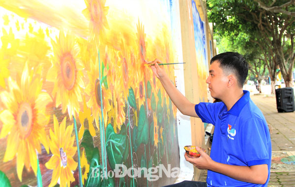 Đoàn viên thanh niên dặm vá lại những vị trí bị nước mưa làm phai màu, chỗ tranh bị bôi bẩn trên bức bích họa trên đường Bùi Thị Xuân, TP.Long Khánh