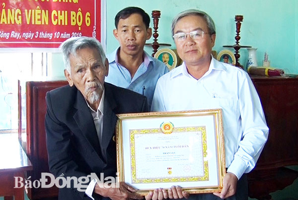 Đồng chí Cao Văn Quang - Bí thư huyện ủy Cẩm Mỹ tặng hoa và trao huy hiệu 70 năm tuổi Đảng cho đồng chí Trần Lục