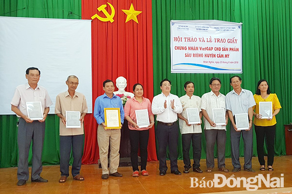 Ông Cao Thọ Tráng (thứ 3 từ phải qua) cùng 7 nông dân khác nhận giấy chứng nhận sản xuất sầu riêng đạt chuẩn VietGAP
