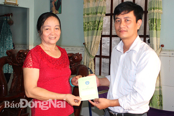 Lãnh đạo Bảo hiểm xã hội huyện Trảng Bom trao sổ bảo hiểm cho bà Nguyễn Thị Lan. Ảnh: B.Mai