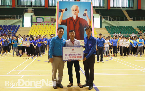 Bí thư Đoàn khối các cơ quan tỉnh Vy Hoài Vũ (bìa phải) trao số tiền tượng trưng tặng 10 suất học bổng cho các học sinh nghèo huyện Thống Nhất