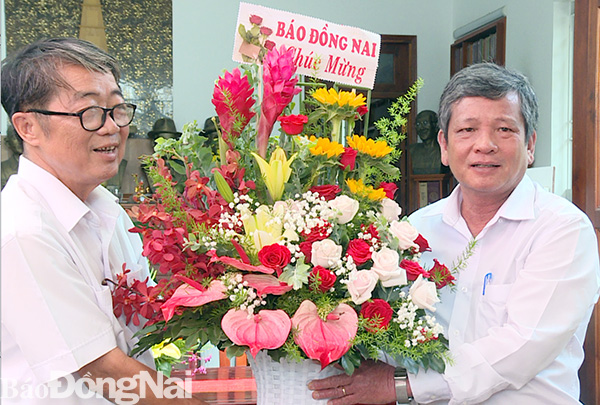 Chủ tịch Hội nhà báo tỉnh, Tổng biên tập Báo Đồng Nai Nguyễn Tôn Hoàn tặng hoa chúc mừng ông Mai Sông Bé