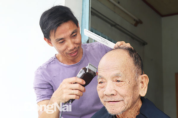 Ông Nguyễn Thanh Liêm (ngụ xã Long Tân, huyện Nhơn Trạch) đến tận nhà cắt tóc miễn phí cho người già bị bệnh, đi lại khó khăn. Ảnh: N.An