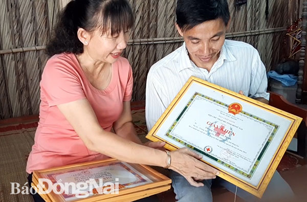 Vợ chồng ông Nguyễn Thanh Liêm xem lại các bằng khen, giấy khen được các cấp trao tặng. Ảnh: N.An