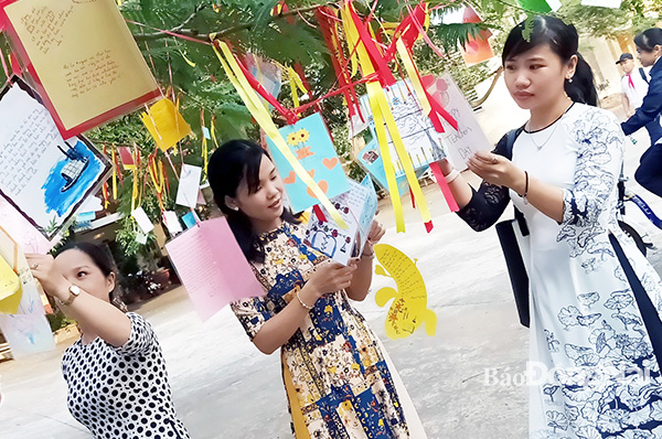 Các giáo viên Trường THCS Long Phước (huyện Long Thành) đón Ngày Nhà giáo Việt Nam đơn giản, tiết kiệm nhưng tràn đầy niềm hạnh phúc bên những tấm thiệp mừng treo trên cây phượng của học trò. Ảnh: Tường Vi