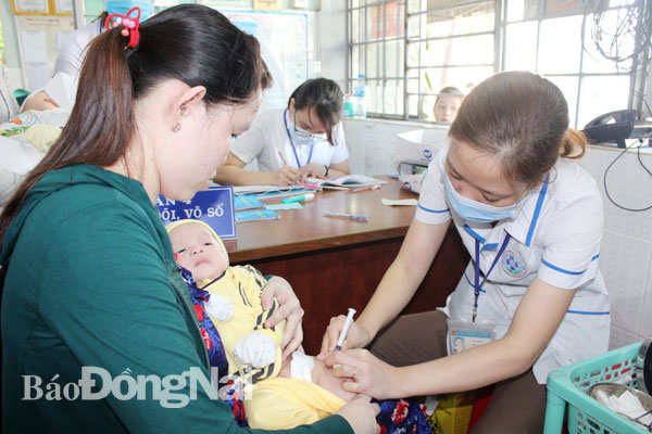 Người dân đưa con trẻ đi chích ngừa tại Trạm y tế phường Trảng Dài, TP.Biên Hòa. Ảnh: A.YÊN