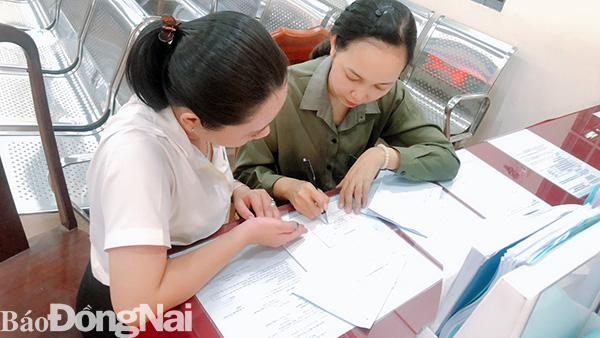 Cán bộ ở bộ phận một cửa huyện Long Thành hỗ trợ người dân làm thủ tục hành chính