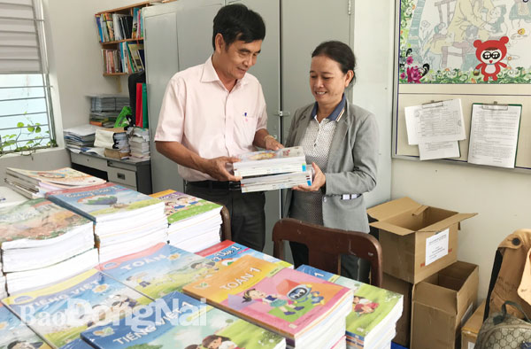 Ông Nguyễn Minh Kiếm, Phó trưởng phòng Nghiệp vụ 1 Sở GD-ĐT trao sách giáo khoa lớp 1 mới cho đại diện Phòng GD-ĐT huyện Long Thành