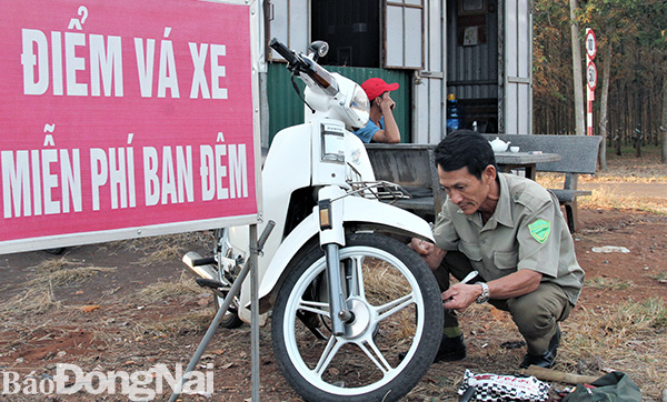 Ông Trần Thanh, Đội trưởng Đội Dân phòng xã Hàng Gòn, TP.Long Khánh đang vá xe miễn phí. Ảnh: Văn Truyên