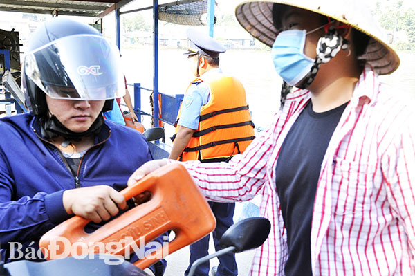 Nhân viên Bến đò Trạm (phường Bửu Long, TP.Biên Hòa) phát dụng cụ nổi cầm tay cho khách đi phà. Ảnh: T.Hải