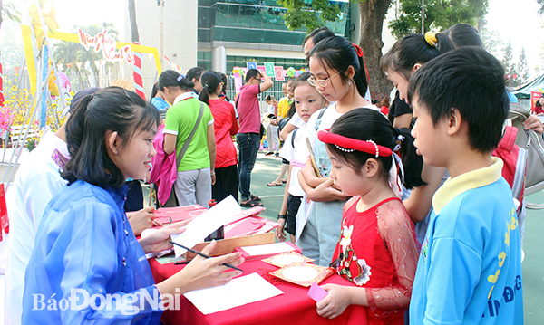 Các em thiếu nhi tham quan gian hàng thư pháp Việt trong chương trình Phiên chợ ngày Tết do Nhà thiếu nhi Đồng Nai tổ chức. Ảnh: Nga Sơn