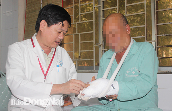 Bác sĩ Nguyễn Tường Quang thăm khám vết thương cho bệnh nhân bị tai nạn giao thông đang điều trị tại khoa. Ảnh: H.Dung