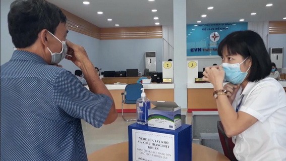 Nhân viên y tế của PC Đồng Nai phát khẩu trang miễn phí và hướng dẫn cách đeo khẩu trang đúng cách cho khách hàng tới giao dịch (Ảnh: CTV)