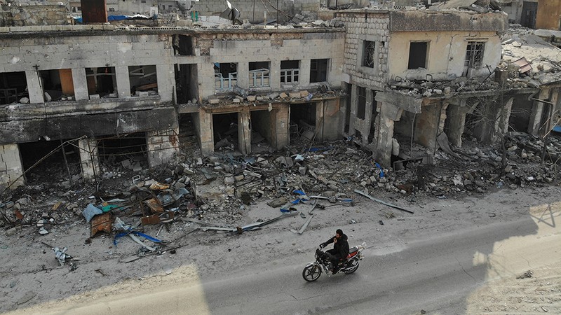 Một người lái xe máy qua những tòa nhà đổ nát ở thị trấn Ihsim tại Idlib, Syria. Ảnh: AFP
