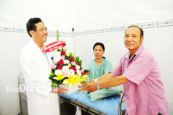 Người nhà bệnh nhân tặng hoa bác sĩ CKII Phan Văn Huyên, Giám đốc Bệnh viện đa khoa khu vực Long Khánh vì đã trực tiếp phẫu thuật, cứu được người thân của họ qua cơn nguy kịch. Ảnh: P.Liễu