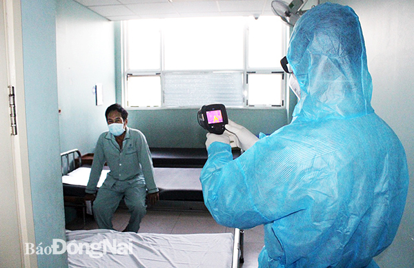 Nhân viên y tế Trung tâm Kiểm soát bệnh tật tỉnh đo thân nhiệt cho những người đang cách ly tại Bệnh viện Đa khoa Đồng Nai