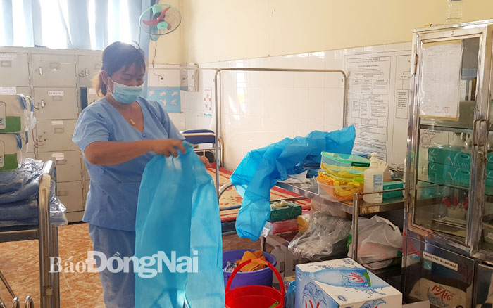 Nhân viên y tế tại khu cách ly ở Cơ sở 2 Trung tâm Y tế H.Vĩnh Cửu mặc đồ bảo hộ chuẩn bị mang đồ dùng vào phòng cho người cách ly