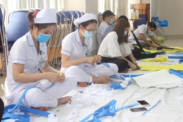 Các y, bác sĩ, nhân viên trẻ của Bệnh viện Đa khoa Đồng Nai đang cắt dán, hoàn thiện các tấm chắn ngăn giọt bắn.