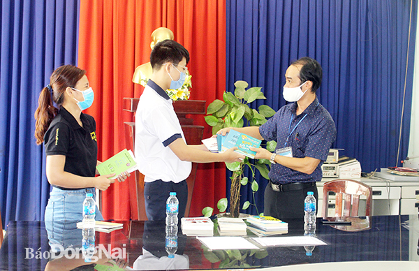 Phó hiệu trưởng Trường THPT Nguyễn Trãi Nguyễn Văn Duyên (bìa phải) nhận sách từ các cá nhân trao tặng trong thời điểm dịch Covid-19. Ảnh: L.NA 