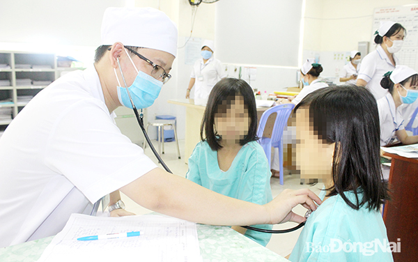 Hai chị em sinh đôi ngụ P.Xuân Trung (TP.Long Khánh) cùng mắc bệnh tan máu bẩm sinh được bác sĩ kiểm tra sức khỏe trước khi thực hiện truyền máu định kỳ. Ảnh: H.Dung