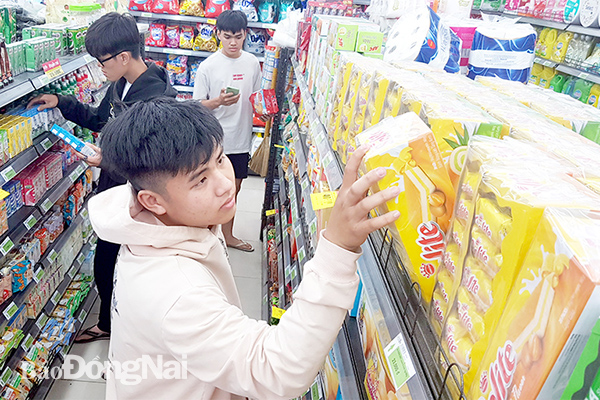 Người tiêu dùng chọn mua một sản phẩm bánh của Việt Nam tại một cửa hàng thuộc chuỗi cửa hàng tiện lợi Co.opFood trên đường Đồng Khởi (TP.Biên Hòa)