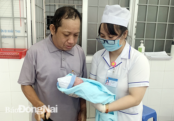 Nhân viên y tế trao em bé cho người đàn ông đã nhặt được bé để người này đi làm thủ tục nhận nuôi em bé   