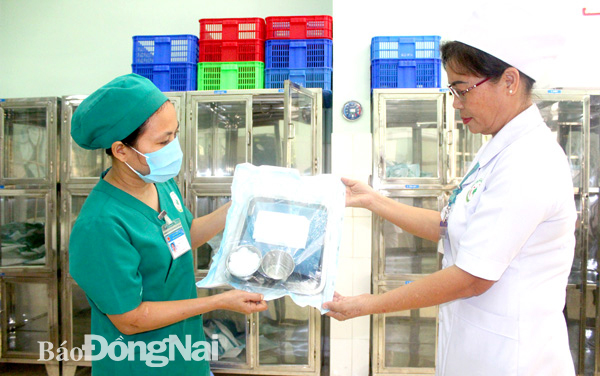 Cử nhân điều dưỡng Đồng Thị Lan, Trưởng khoa Kiểm soát nhiễm khuẩn Bệnh viện Nhi đồng Đồng Nai (phải) kiểm tra dụng cụ, quần áo sau khi được khử khuẩn, tiệt khuẩn